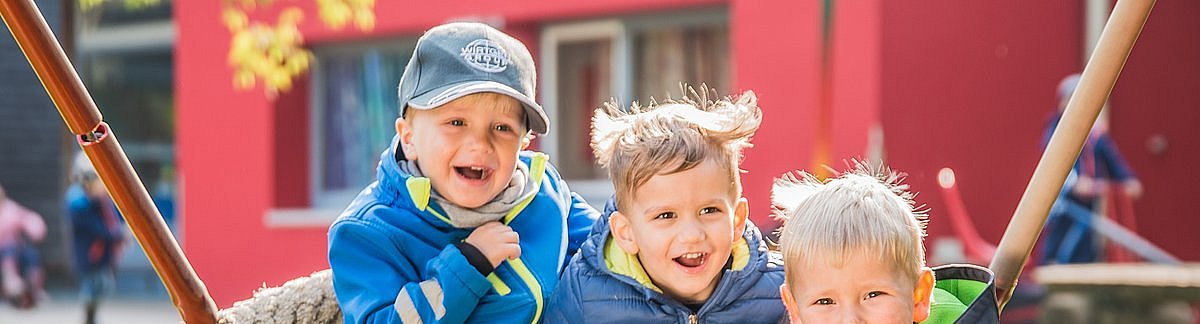 lachende Kita-Kinder in Nestschaukel